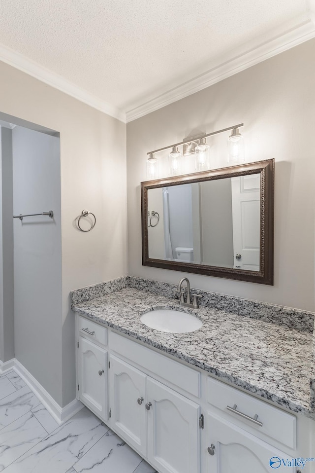 bathroom with a textured ceiling, vanity, baseboards, marble finish floor, and crown molding