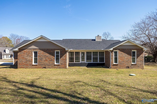 back of house with a yard, brick siding, a chimney, and roof with shingles