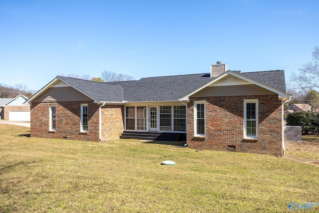 back of house with entry steps, brick siding, a yard, and a chimney