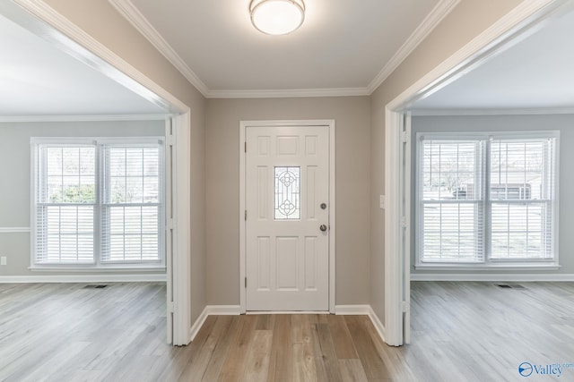 entrance foyer featuring crown molding, light wood finished floors, visible vents, and a healthy amount of sunlight