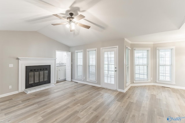 unfurnished living room with a glass covered fireplace, vaulted ceiling, light wood-style flooring, and baseboards