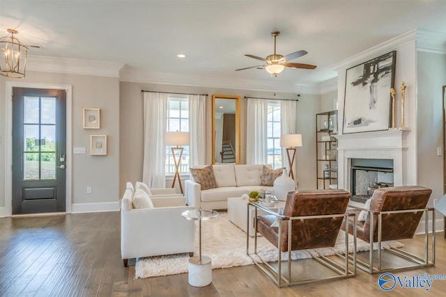 living room featuring wood-type flooring, ornamental molding, and ceiling fan with notable chandelier