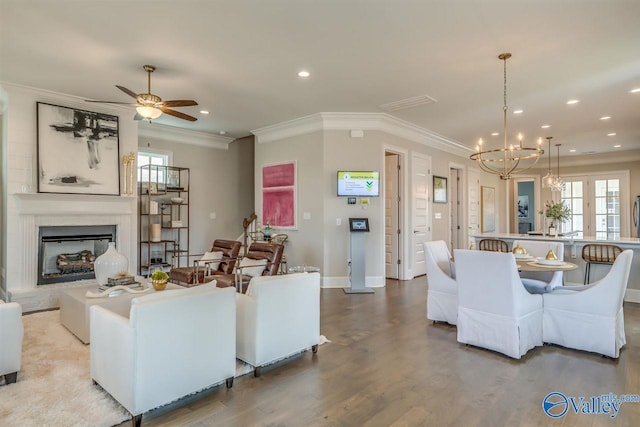 living room with light hardwood / wood-style floors, crown molding, and ceiling fan with notable chandelier