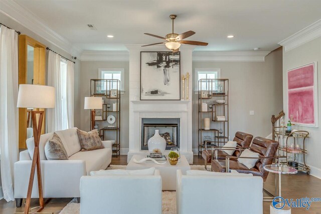 living room with a wealth of natural light, ornamental molding, hardwood / wood-style floors, and a large fireplace