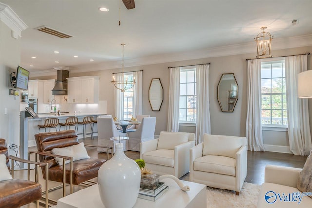 living room with a healthy amount of sunlight, ornamental molding, and light wood-type flooring