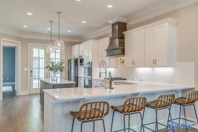 kitchen with dark hardwood / wood-style floors, hanging light fixtures, kitchen peninsula, a breakfast bar, and white cabinets