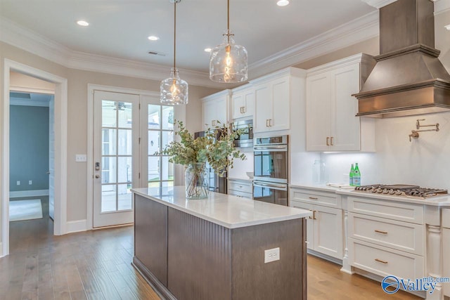 kitchen featuring appliances with stainless steel finishes, white cabinets, custom range hood, and light wood-type flooring