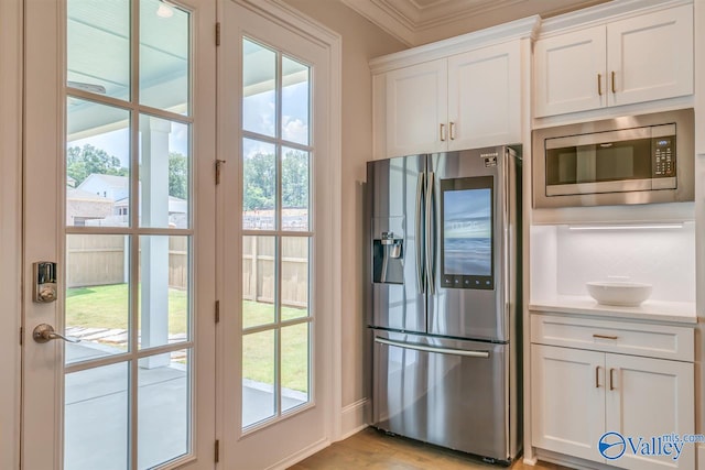 kitchen with ornamental molding, light hardwood / wood-style flooring, white cabinets, and stainless steel appliances