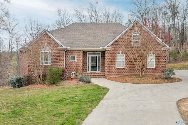 view of front facade featuring brick siding, concrete driveway, a front lawn, and a shingled roof