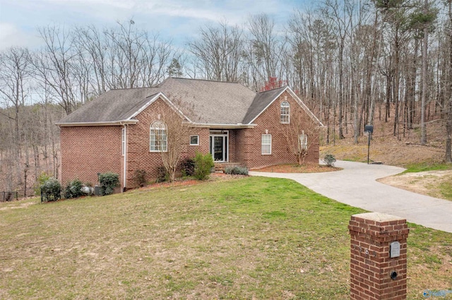 view of front of home featuring brick siding, roof with shingles, concrete driveway, and a front lawn