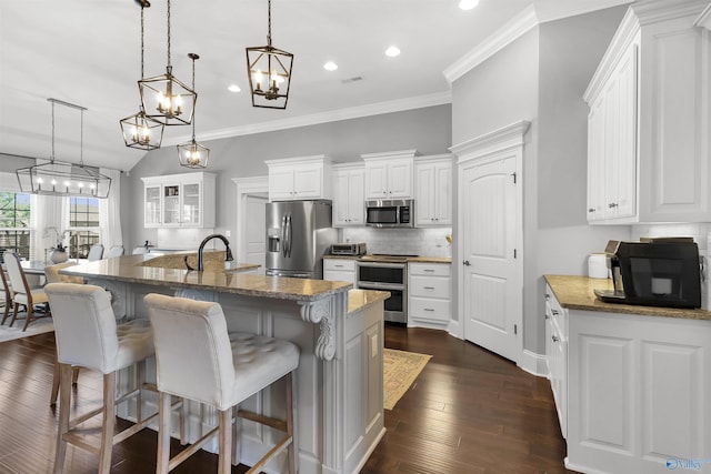 kitchen with decorative backsplash, ornamental molding, a kitchen bar, white cabinetry, and stainless steel appliances