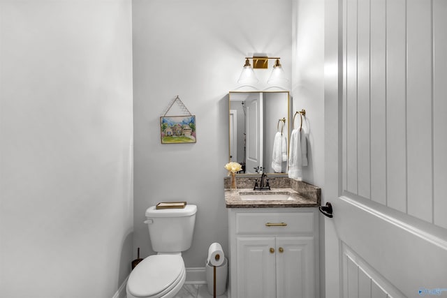 half bathroom featuring vanity, baseboards, and toilet