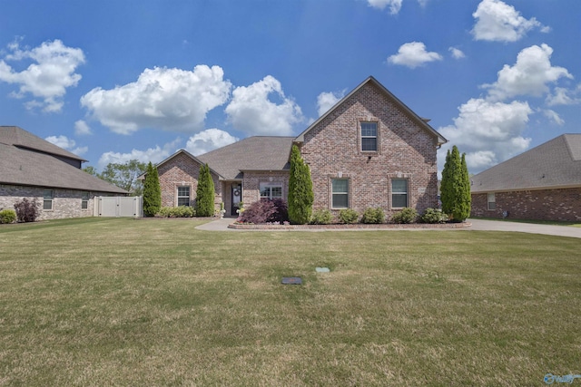view of front of home with brick siding, fence, and a front yard