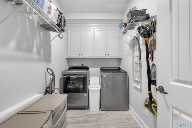 laundry area with independent washer and dryer, baseboards, marble finish floor, and cabinet space