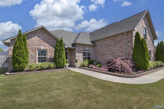 view of front of home featuring brick siding, a shingled roof, and a front yard
