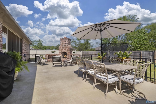 view of patio with a fenced backyard, an outdoor brick fireplace, and grilling area