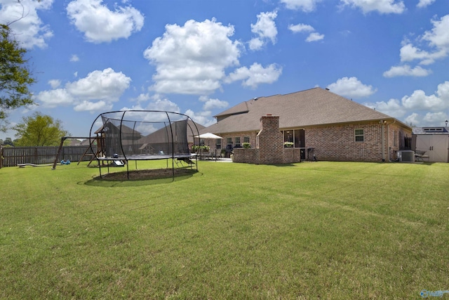 view of yard featuring central AC, fence private yard, and a trampoline