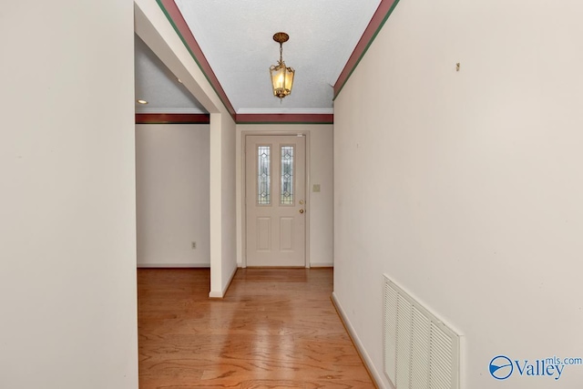 foyer with light hardwood / wood-style floors and crown molding