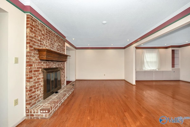 unfurnished living room featuring a fireplace, wood-type flooring, a textured ceiling, and crown molding