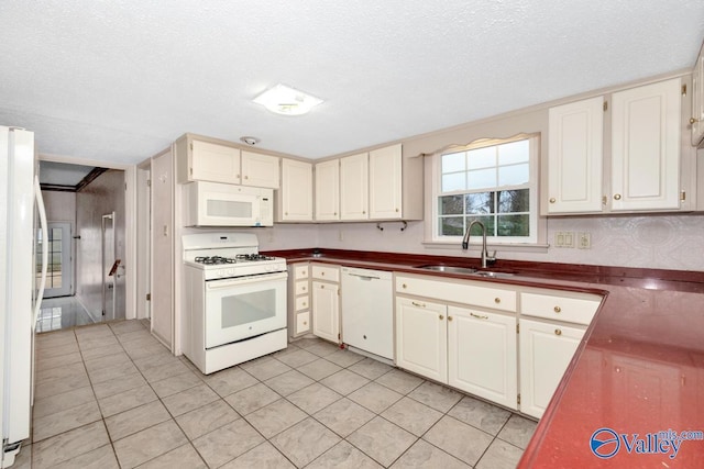 kitchen with a textured ceiling, light tile patterned flooring, white appliances, and sink