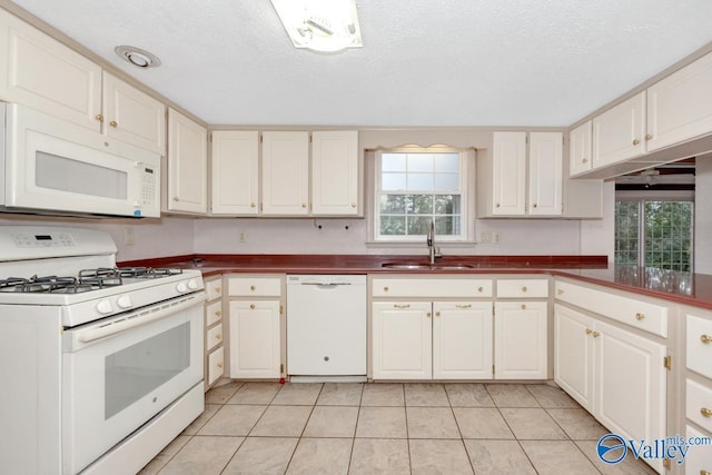 kitchen featuring a healthy amount of sunlight, white appliances, sink, and white cabinetry