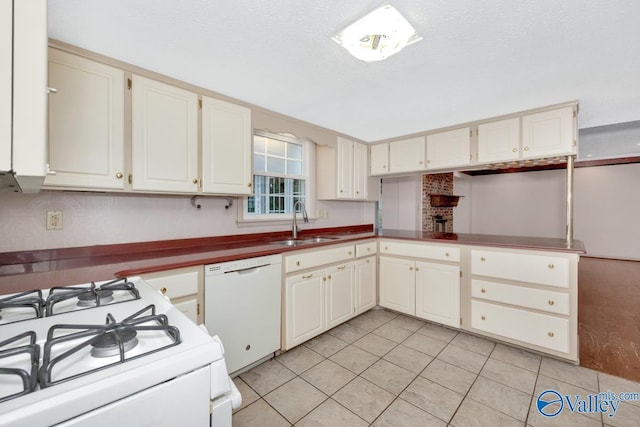 kitchen featuring kitchen peninsula, white appliances, a textured ceiling, sink, and light tile patterned floors