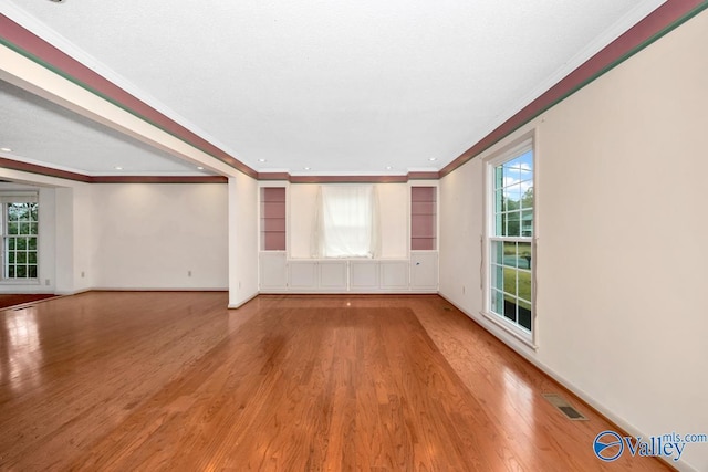 unfurnished living room featuring crown molding, wood-type flooring, and a textured ceiling