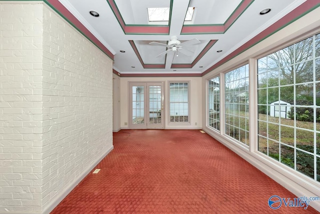 unfurnished sunroom featuring a tray ceiling, a skylight, and ceiling fan