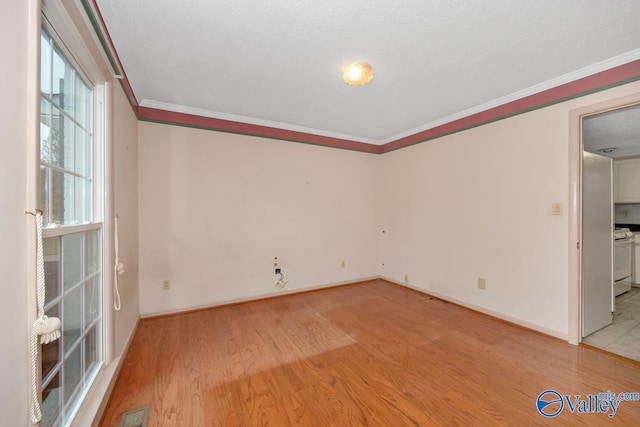 spare room featuring light hardwood / wood-style floors, a textured ceiling, and ornamental molding