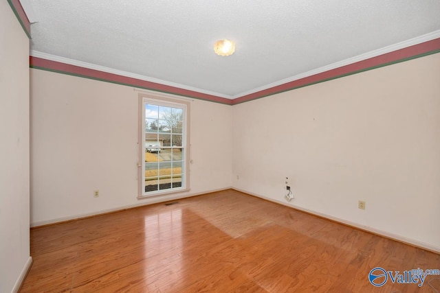 spare room featuring crown molding, a textured ceiling, and light wood-type flooring