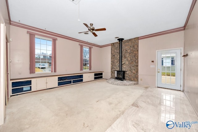 living room with a wood stove, a wealth of natural light, ceiling fan, and ornamental molding