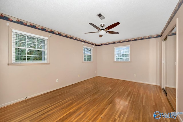 unfurnished room featuring hardwood / wood-style floors, ceiling fan, and a textured ceiling