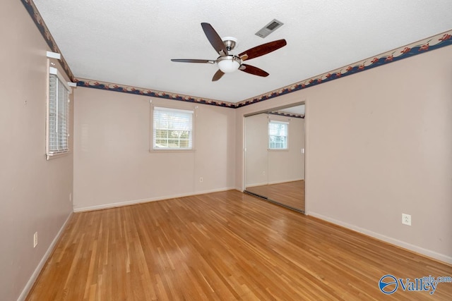 unfurnished room featuring ceiling fan, light hardwood / wood-style floors, and a textured ceiling