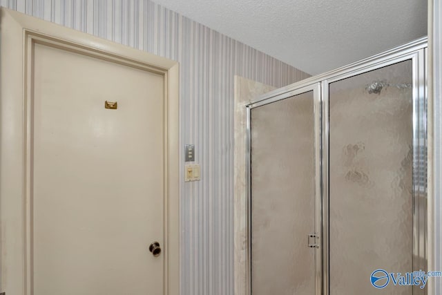 bathroom featuring a textured ceiling and a shower with shower door