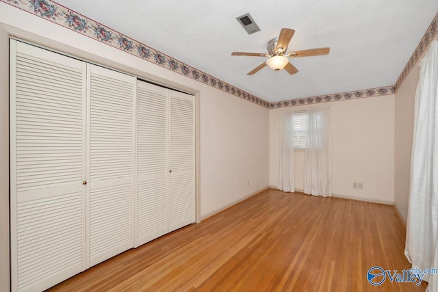 unfurnished bedroom with ceiling fan, a closet, wood-type flooring, and a textured ceiling