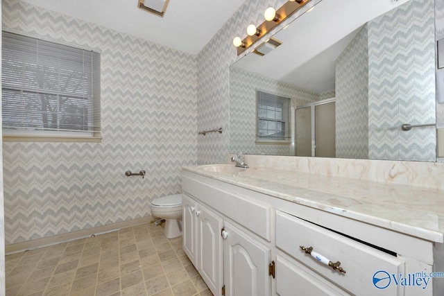 bathroom featuring a shower with door, vanity, and toilet