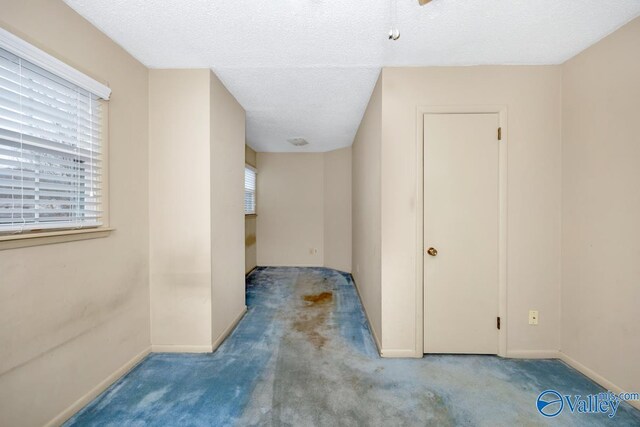 hallway featuring light colored carpet and a textured ceiling