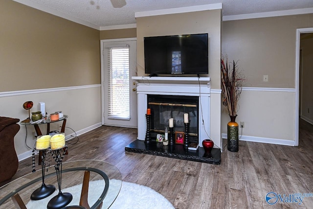 living room featuring baseboards, a textured ceiling, wood finished floors, and a glass covered fireplace
