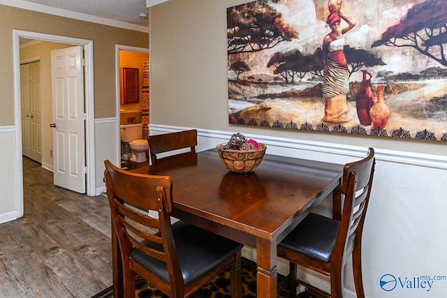 dining area featuring a textured ceiling, baseboards, and wood finished floors