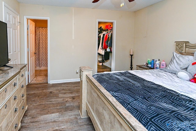 bedroom with a closet, ensuite bathroom, baseboards, dark wood finished floors, and a spacious closet