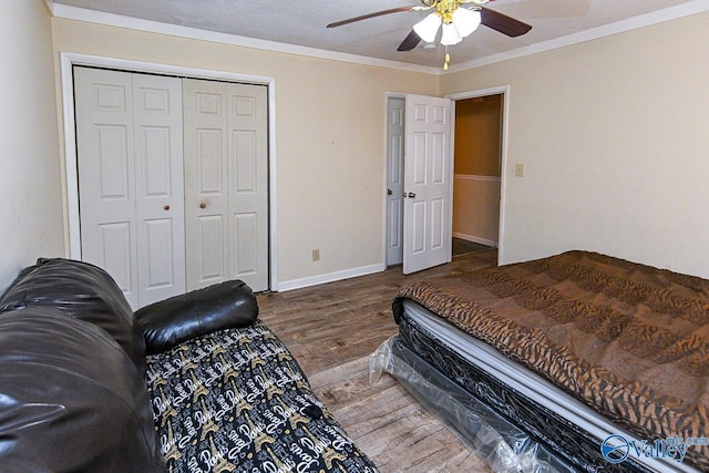 bedroom featuring crown molding, a closet, wood finished floors, baseboards, and ceiling fan