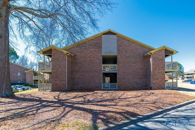 back of house featuring a balcony and brick siding