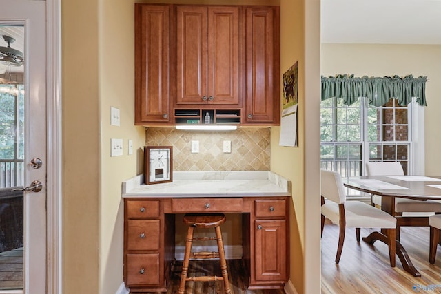 kitchen with light hardwood / wood-style flooring, light stone countertops, a healthy amount of sunlight, and decorative backsplash