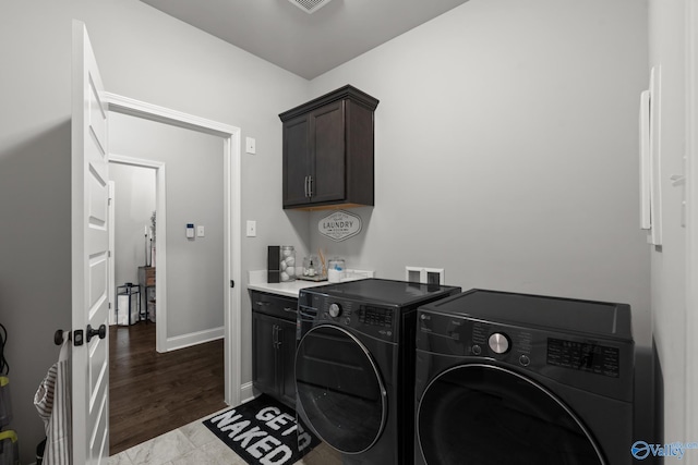 clothes washing area featuring dark hardwood / wood-style flooring, cabinets, and washing machine and dryer