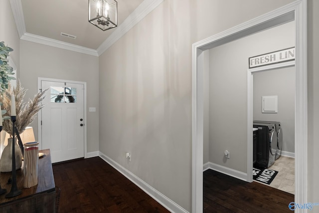 foyer entrance featuring ornamental molding, washing machine and dryer, dark wood-type flooring, and a notable chandelier