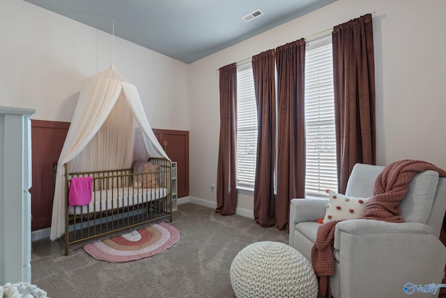 bedroom with light colored carpet and a nursery area