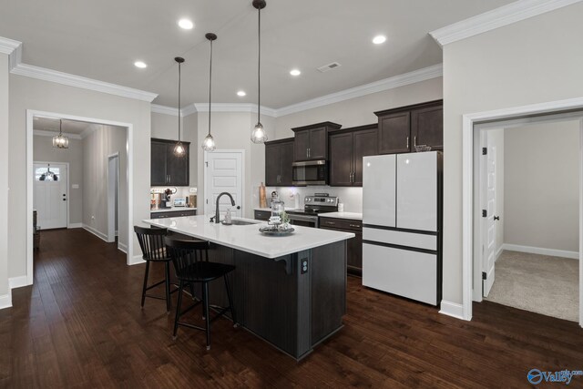 kitchen with sink, hanging light fixtures, stainless steel appliances, an island with sink, and a breakfast bar