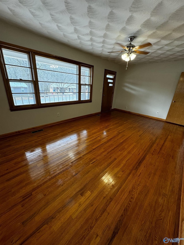 unfurnished room with hardwood / wood-style flooring, ceiling fan, and a textured ceiling