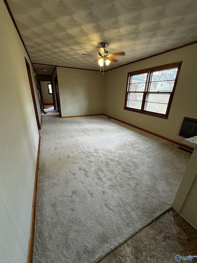 unfurnished living room with ceiling fan, ornamental molding, a textured ceiling, and carpet flooring