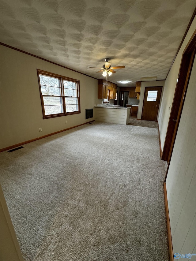 unfurnished living room featuring ornamental molding, a healthy amount of sunlight, and carpet flooring